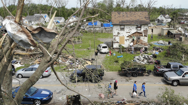 Residents walk through a tornado damaged neighborhood, Wednesday, May 29, 2019, in Dayton, Ohio, as clean up efforts begin. Tens of thousands of Ohio residents were still without power or water in the aftermath of strong tornadoes that spun through the Midwest earlier in the week. (AP Photo/John Minchillo)