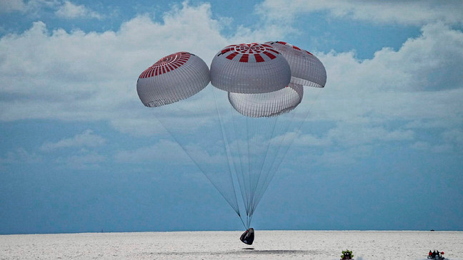 In this image taken provided by SpaceX, a capsule carrying four people parachutes into the Atlantic Ocean off the Florida coast, Saturday, Sept. 18, 2021. The all-amateur crew was the first to circle the world without a professional astronaut.  (SpaceX via AP)