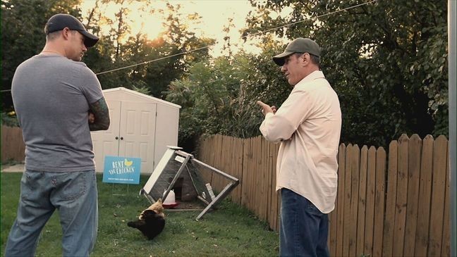 Two men talk in a backyard with a Rent the Chicken sign and two chickens seen in the background. (Photo courtesy: Rent the Chicken)