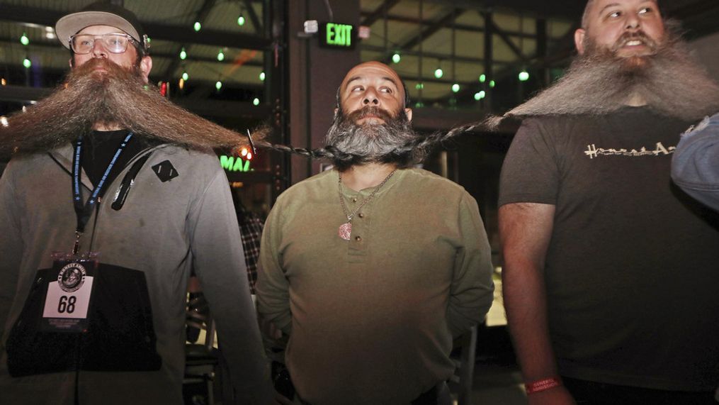 Men wait for the chain of their beards to be measured as part of their attempt at breaking the world's longest beard chain in the Guinness Book of World Records, Friday, Nov. 11, 2022, at The Gaslight Social in Casper, Wyo. (Lauren Miller/The Casper Star-Tribune via AP)