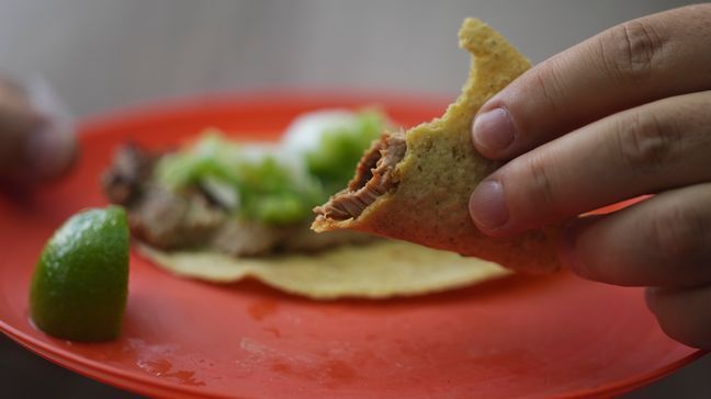 A customer holds his partially eaten taco at the Tacos El Califa de  León taco stand, in Mexico City, Wednesday, May 15, 2024.  Tacos El Califa de León is the first ever taco stand to receive a Michelin star from the French dining guide. (AP Photo/Fernando Llano)