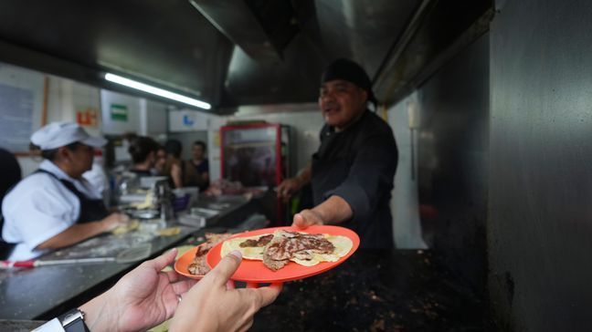 Newly minted Michelin-starred chef Arturo Rivera Martínez hands a customer his order of tacos at the Tacos El Califa de  León taco stand, in Mexico City, Wednesday, May 15, 2024.  Tacos El Califa de León is the first ever taco stand to receive a Michelin star from the French dining guide. (AP Photo/Fernando Llano)